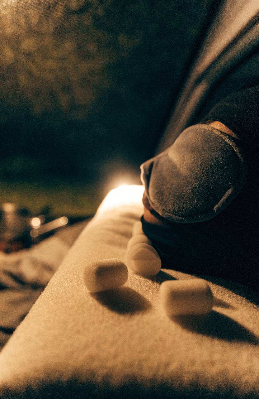Earplugs and an eye mask on a pillow in a car camping bed