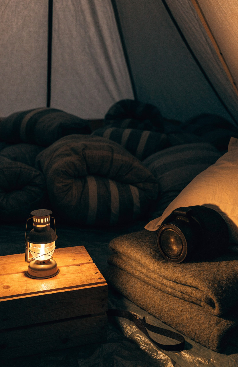 Dim lantern and headlamp glowing inside cozy tent at night