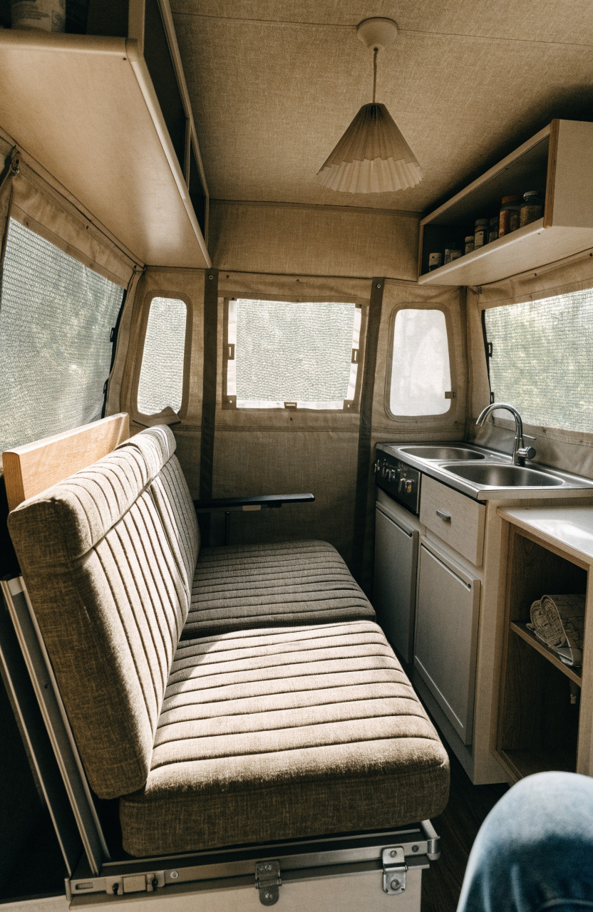 Cozy tent trailer interior with dinette, small kitchen and canvas bunk